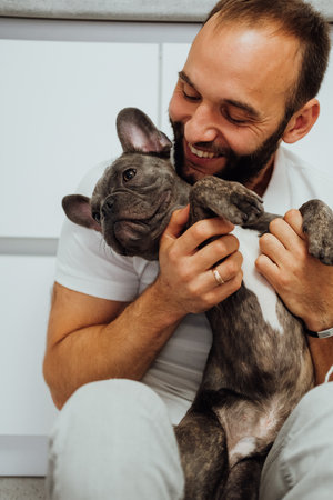 Cheerful Caucasian Man Hugging His Lovely Pet French Bulldogの写真素材