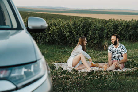 Happy middle-aged couple having picnic outside the city, cheerful man and caucasian woman enjoying weekend together on a road tripの写真素材