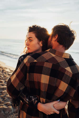 Young woman and man hugging on the background of the sea and sunlight