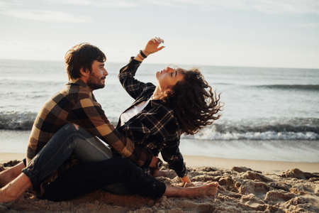 Young adult couple fall in love, curly haired woman sitting on man and enjoying being together on...