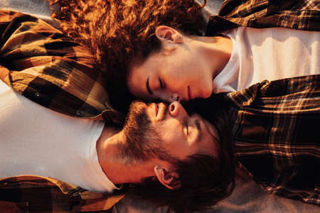 View from above, young couple in love lying facing each other and morning sunlight shines on them