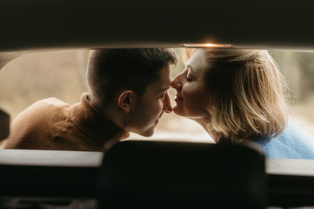 Intimate moment woman and man sitting in the open trunk of a car while traveling in autumn and...