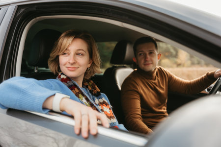 Adult couple on a autumn road trip, man and woman sitting in the car and looking through the window