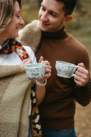 Man and a woman outdoors standing together smiling, holding handmade ceramic tea cupsの写真素材