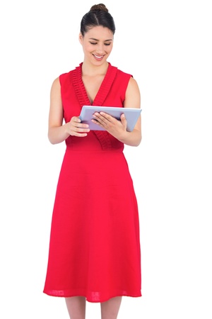 Content elegant brunette in red dress on white background holding tablet pcの写真素材
