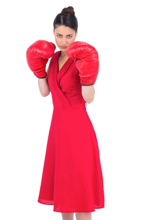 Elegant brunette in red dress wearing boxing gloves posing on white backgroundの写真素材