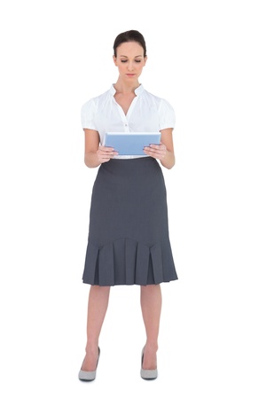 Focused pretty businesswoman using tablet computer while posing on white backgroundの写真素材