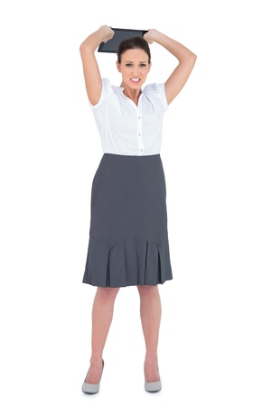 Furious businesswoman throwing her tablet pc while posing on white backgroundの写真素材