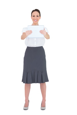 Cheerful businesswoman holding her tablet pc while posing on white backgroundの写真素材
