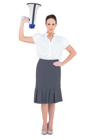 Serious businesswoman holding megaphone while posing on white backgroundの写真素材