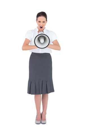 Angry businesswoman shouting in her megaphone while posing on white backgroundの写真素材