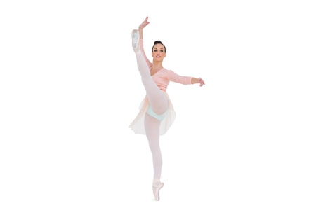 Smiling gorgeous ballerina rising her leg on white background の写真素材