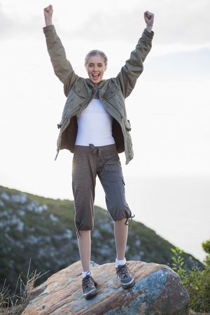 Cheering woman standing on a rock looking at camera in the countrysideの写真素材