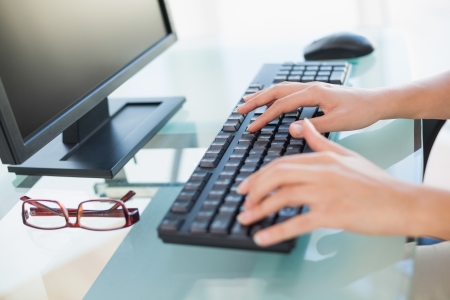 Close up of female hands typing on keyboard at desk in her workplaceの写真素材