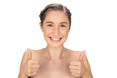 Smiling woman giving thumbs up to camera on white backgroundの写真素材