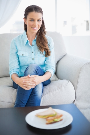 Calm pretty woman sitting on sofa in bright living roomの写真素材