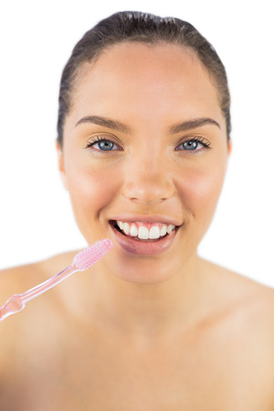 Happy woman brushing her teeth against white backgroundの写真素材