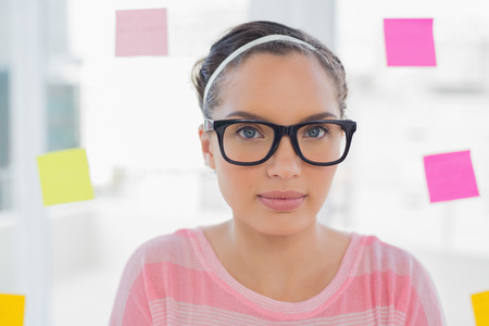 Serious woman with glasses in creative office looking at camera