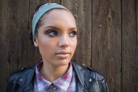Close up view of attractive woman looking away in front of a wooden doorの写真素材