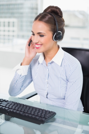 Happy businesswoman using headset in bright officeの写真素材