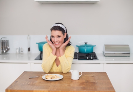 Surprised gorgeous brunette having dessert posing in bright kitchenの写真素材
