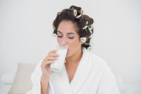 Calm natural brunette drinking glass of milk in bedroomの写真素材