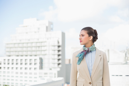 Thoughtful smart brown haired businesswoman looking away outdoorsの写真素材
