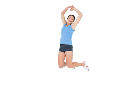 Full length portrait of a sporty young woman jumping over white background