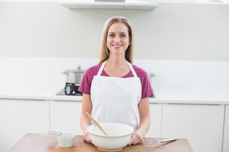 Casual smiling model standing behind baking utensils in bright kitchenの写真素材