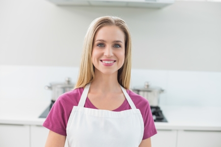 Casual smiling blonde looking at camera standing in kitchenの写真素材