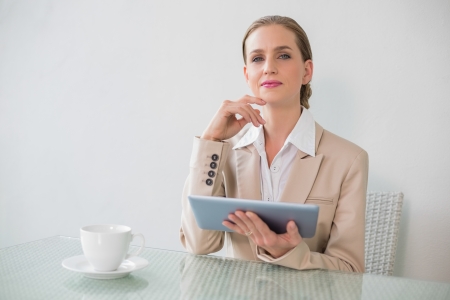 Content stylish businesswoman holding tablet in bright officeの写真素材