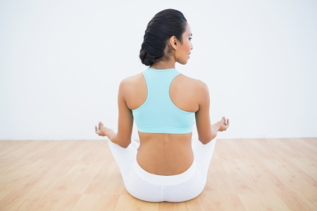 Rear view of calm woman meditating in lotus position in fitness hallの写真素材