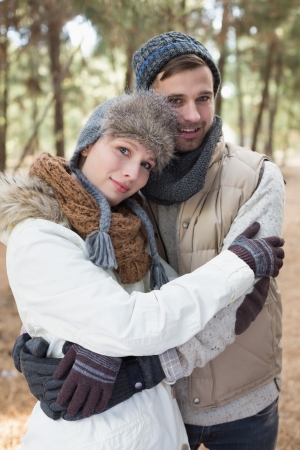 Loving young couple in winter clothing embracing in the woodsの写真素材