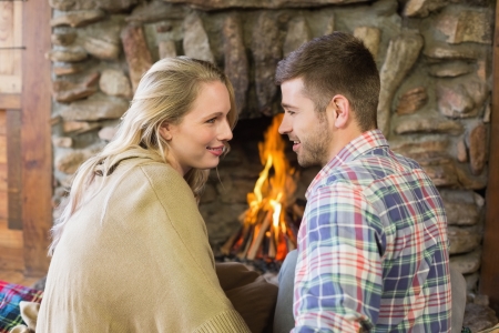 Side view of a loving young couple looking at each other in front of lit fireplaceの写真素材