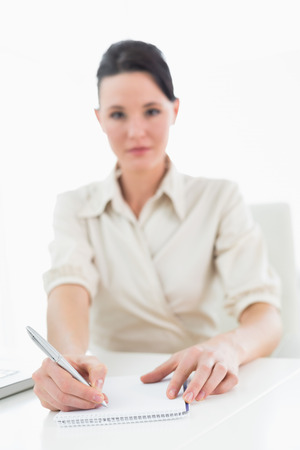 Portrait of a young businesswoman writing notes by laptop over white backgroundの写真素材