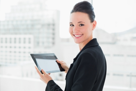 Close up portrait of an elegant businesswoman with tablet PC in a bright officeの写真素材