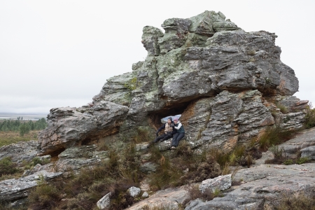 Distance shot of a young couple on huge rock while on a hikeの写真素材