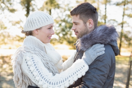 Side view of a loving young couple looking at each other in winter clothing in the woodsの写真素材