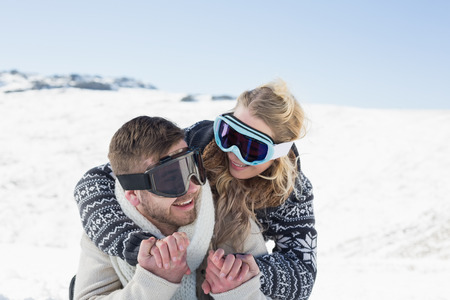 Close up of a cheerful man and woman in ski goggles on snow covered landscapeの写真素材