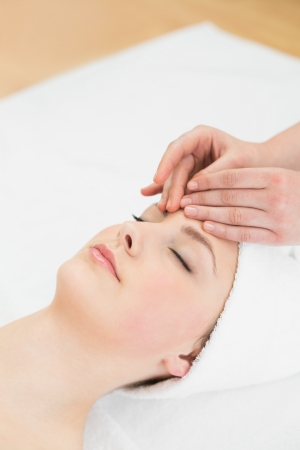 Close up of hands massaging a beautiful womans forehead at beauty spaの写真素材