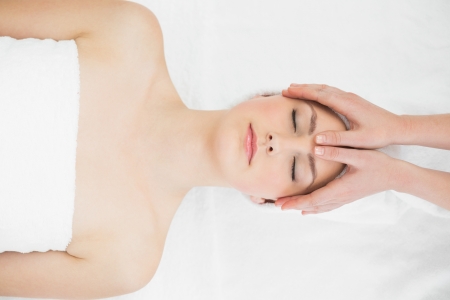 Close up of hands massaging a beautiful womans forehead at beauty spaの写真素材