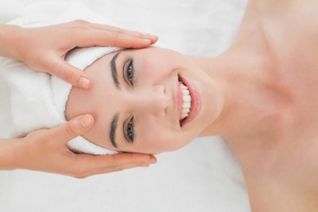 Close up of hands massaging a beautiful womans forehead at beauty spaの写真素材