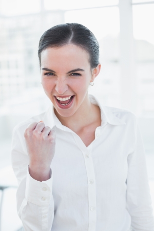 Portrait of a cheerful elegant businesswoman cheering in a bright officeの写真素材