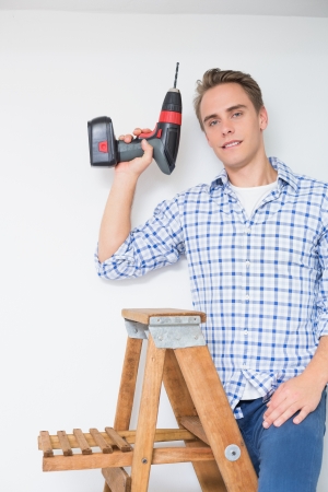 Portrait of a young handsome handyman using cordless drill to the ceilingの写真素材