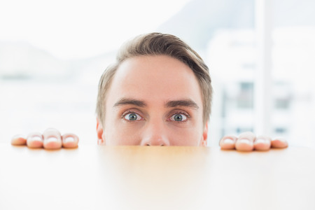 Close up portrait of a young businessman looking over blurred wall at bright officeの写真素材