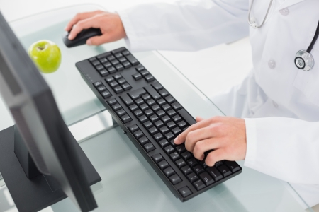 Close up mid section of doctor using computer at medical officeの写真素材