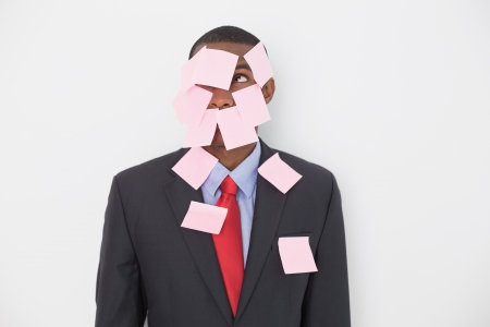 Young Afro businessman covered in blank notes over white backgroundの写真素材