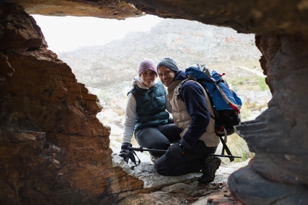 Portrait of a smiling young couple seen through rock cave while on a hikeの写真素材