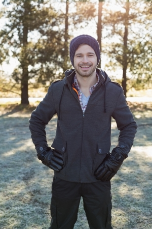 Portrait of a young man in warm clothing while having a walk in forest on a winter dayの写真素材