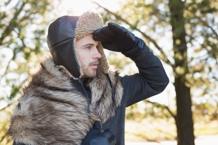 Young man in warm clothing looking away in forest on a winter day